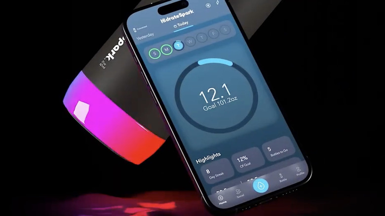 The glowing base of a HidrateSpark bottle, and the interface of its accompanying smartphone app shown on a smartphone screen