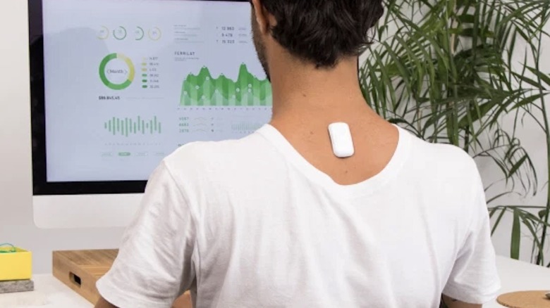 The Upright 2 Go device shown stuck on the back of a man working at a computer