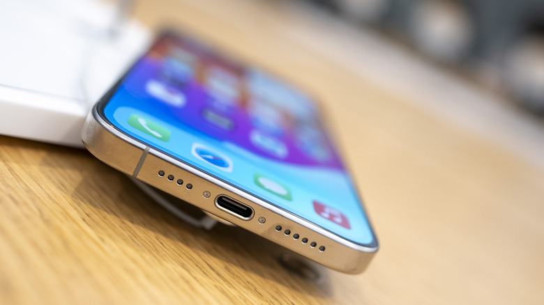 An iPhone 15 with a USB Type-C charging port on a table