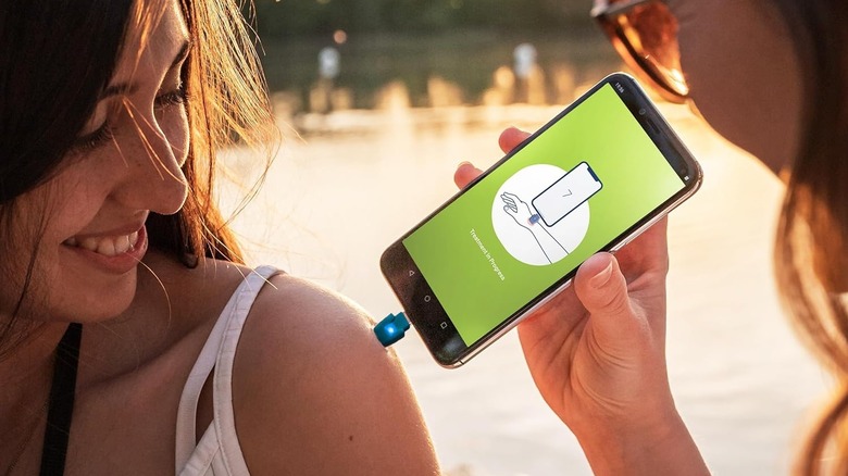 A person using Heat It's USB Insect Bite Healer with their smartphone