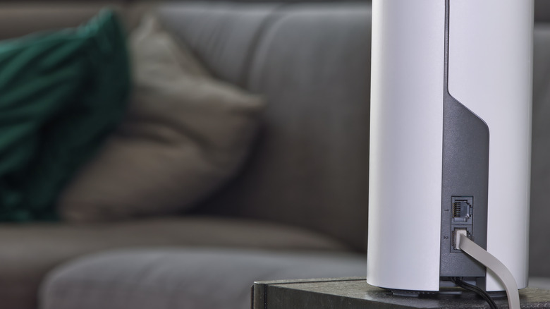 A mesh Wi-Fi satellite router that looks like a white upright cylinder plugged in with an Ethernet cable