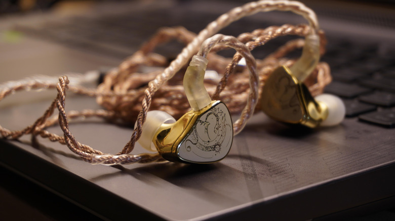 A pair of high-end earbuds sitting on a laptop
