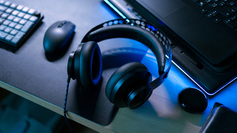 A pair of wired gaming headphones sitting atop a computer desk