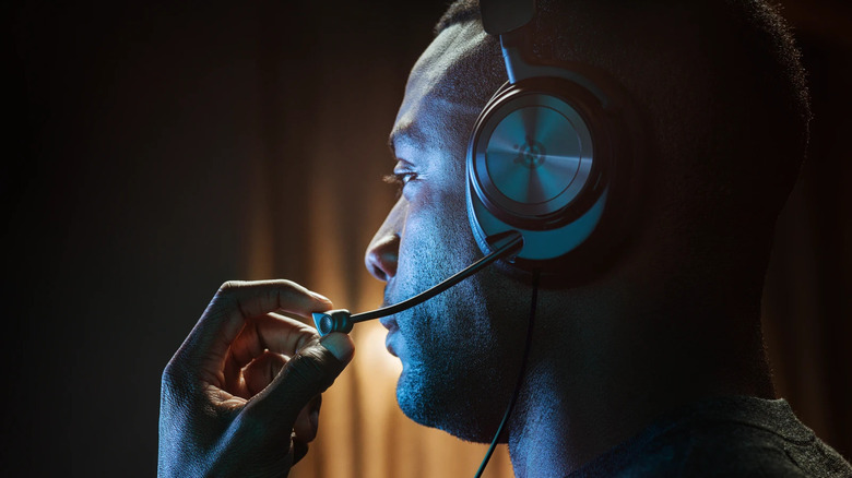 A person wearing the SteelSeries Arctis Nova Pro wired gaming headset and adjusting the microphone