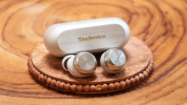 The Technics EAH-AZ100 buds and case placed on a wooden coaster.