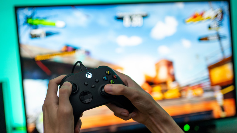 Xbox Series X controller in front of a TV with a blurred game