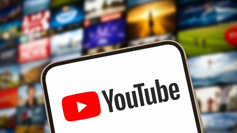 The YouTube logo appears on a smartphone, behind it is a series of images showing various content, though the background is too blurry to fully indicate exactly what is being displayed