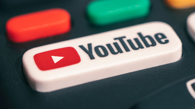 An extreme closeup of a YouTube button on a television's remote control, the white button is the YouTube logo
