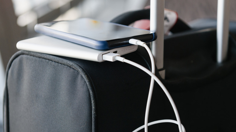 Phone plugged into power bank resting atop luggage.
