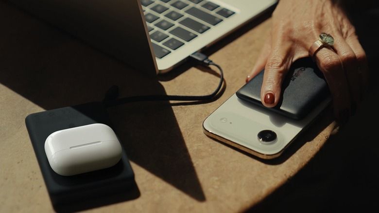 A Baseus power bank charging an earpods case and a laptop while another power bank is attached to an iPhone Air