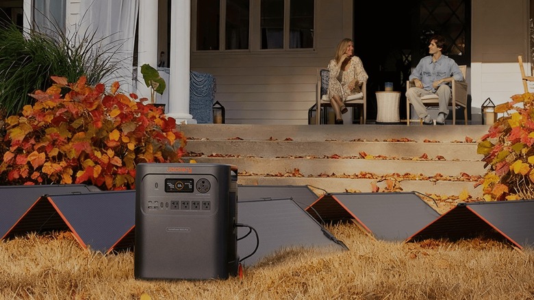 A Jackery power station with solar panels in front of the porch of a house