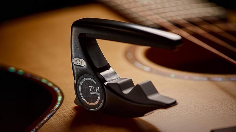 A black G7th Performance 3 capo resting atop an acoustic guitar.