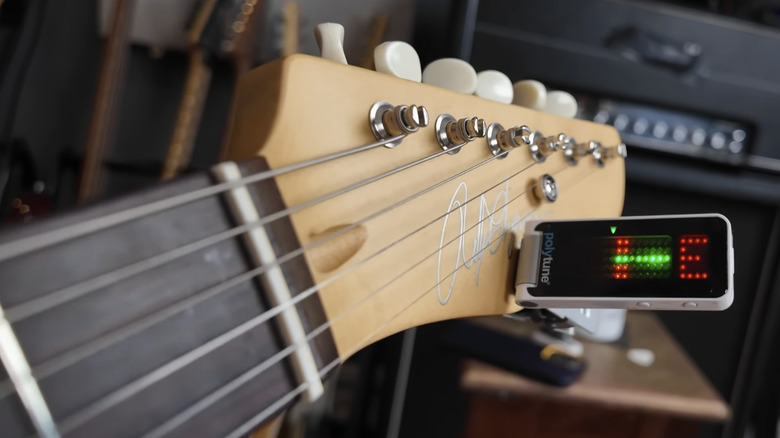 A beige guitar headstock with a Polytune Clip tuner clipped onto it.