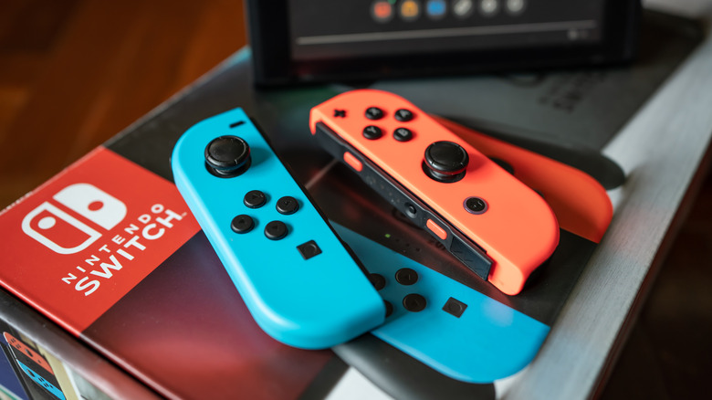 A pair of red and blue Joy-Cons sit next to each other on top of a Nintendo Switch box, the bottom of the console can sort of be seen just out of frame