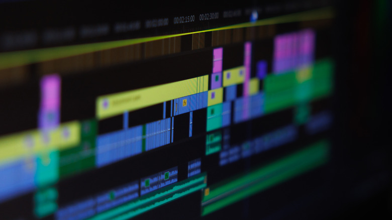 A close-up of a video editing timeline on a computer screen, showing multiple colorful tracks and clips arranged across a project sequence.
