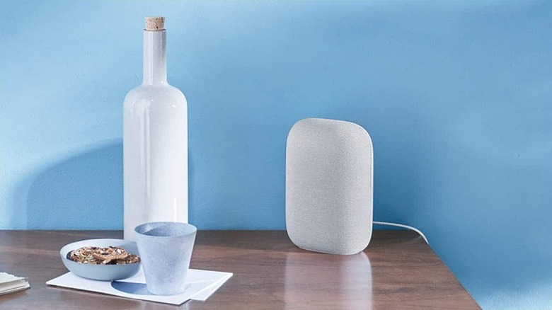 Nest speaker placed on a wooden table alongside breakfast bowl.