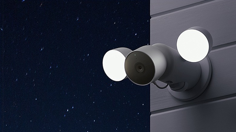 Security camera with two floodlights mounted outdoors.