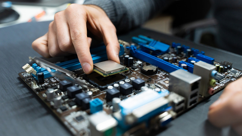 A person setting a CPU into a motherboard.