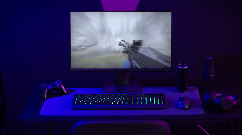 A gaming PC setup with RGB gaming peripherals and an FPS game being played on the monitor.