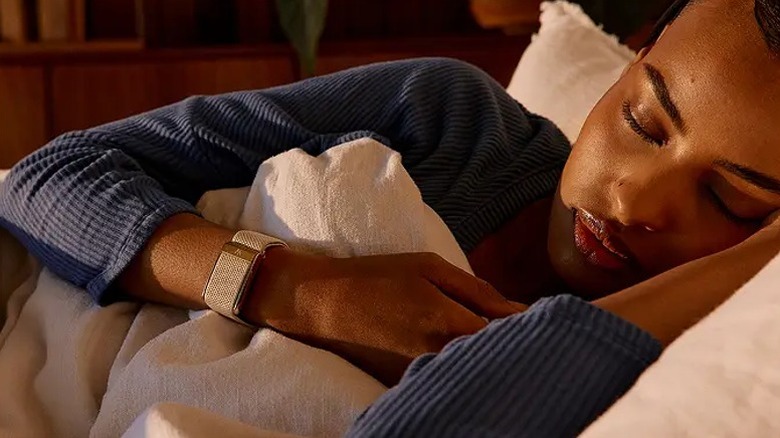 A woman sleeping on her side wearing a rose gold Whoop 5.0 band.
