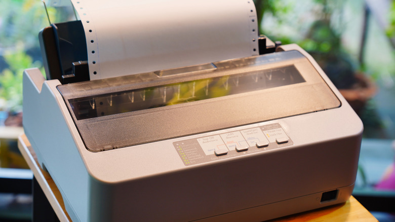A dot-matrix printer loaded with a sheet of tractor-feed paper.