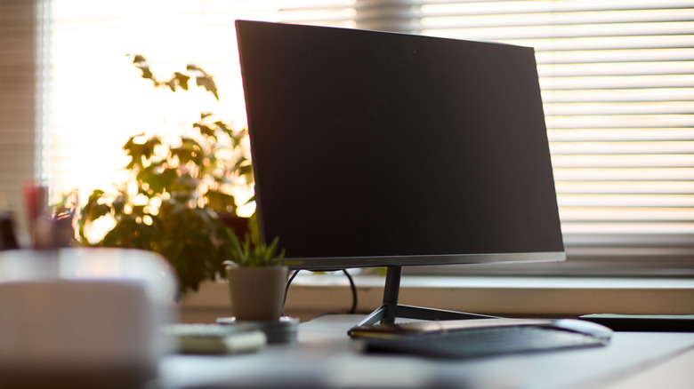A computer monitor and keyboard sits on a desk.