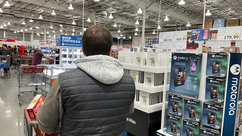A person browsing the electronics section at a Costco store in Canada.