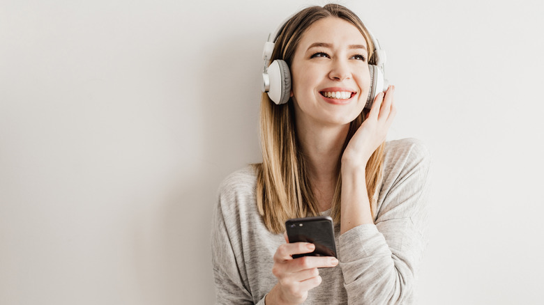 A person smiling while listening to music with wireless headphones.