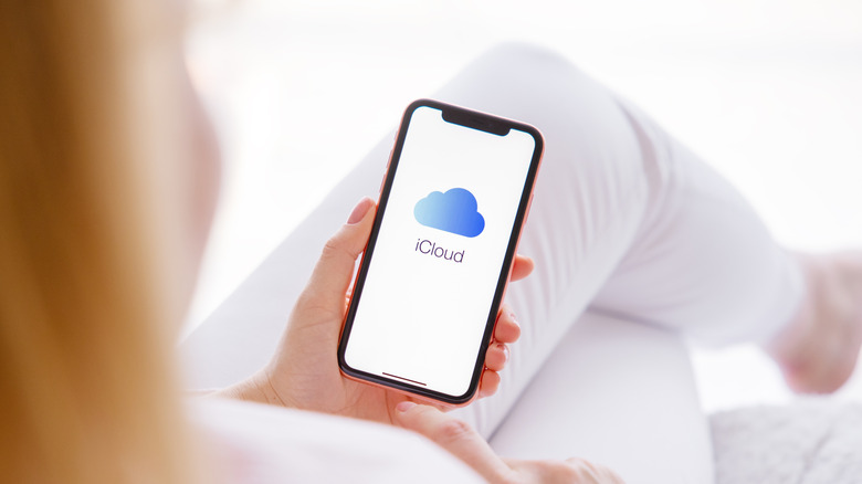 A woman holding an iPhone with the iCloud logo.