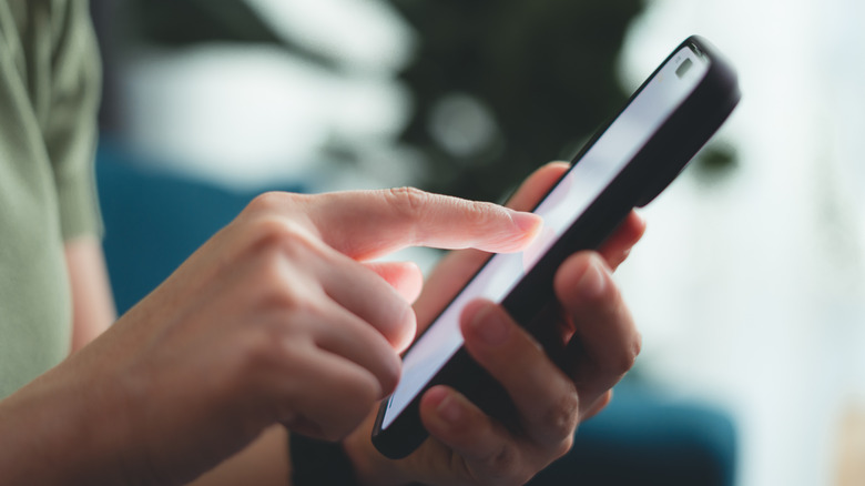 A side view of a person's finger on a phone.