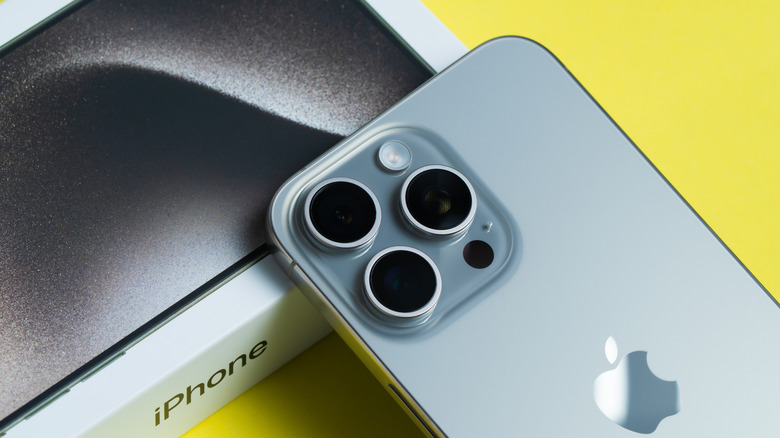 An iPhone leaning face down atop its box.