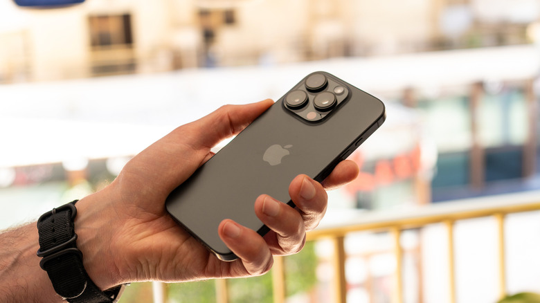 A hand holding an iPhone face down.