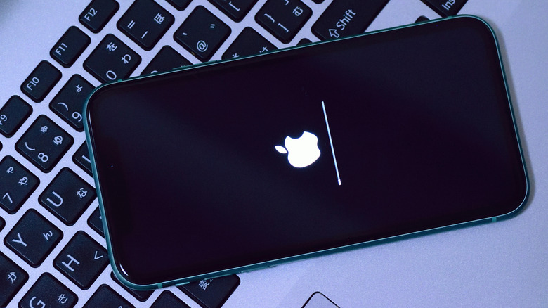 An iPhone atop a keyboard with the screen showing a reload update in progress.