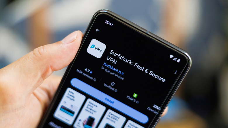 Man holding phone showing Surfshark VPN in Google Play Store