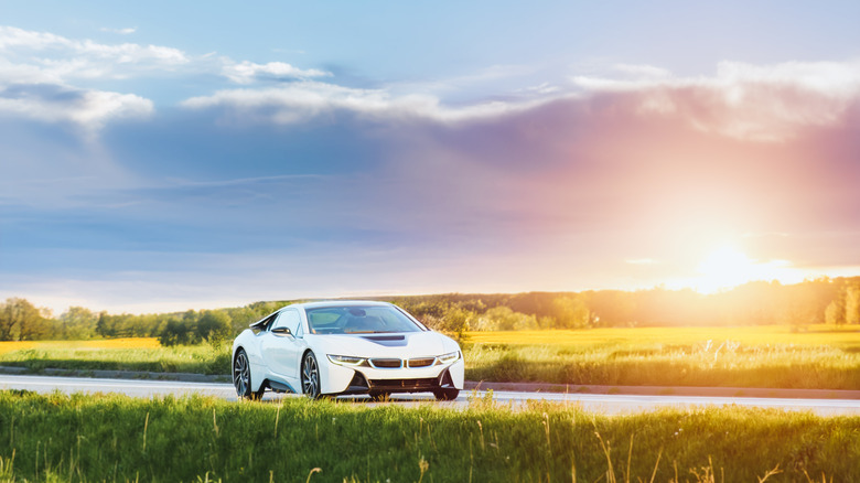 An electric car driving down the road with the sun in the background.