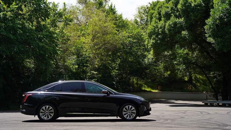 An electric car on the road with a background of trees.
