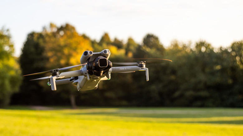 The DJI Mini 5 Pro drone flying over a grass field
