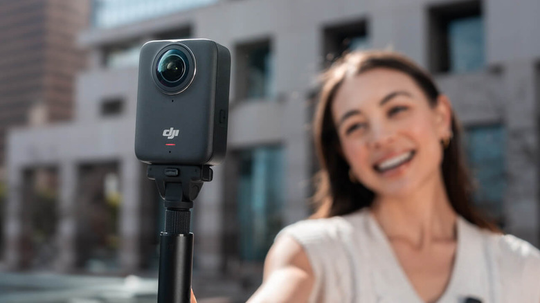 A person smiling and holding the DJI Osmo 360 camera