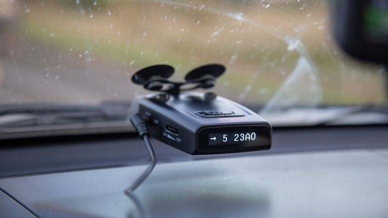 A radar detector mounted to the windshield of a car.