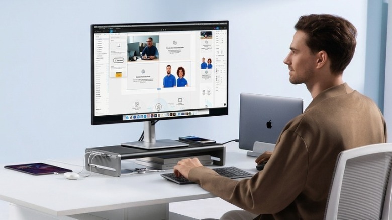 A person sitting at their desk with the Anker 675 docking station connected to a MacBook, Monitor, and other gadgets.