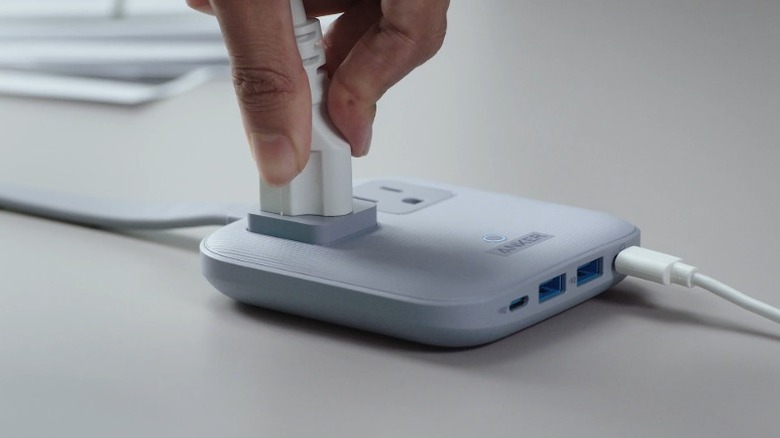 A person plugging in a power cord into the Anker Nano Travel Power Strip
