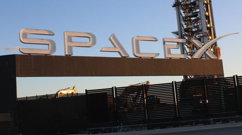 The SpaceX logo is visible with a rocket gantry in the background.