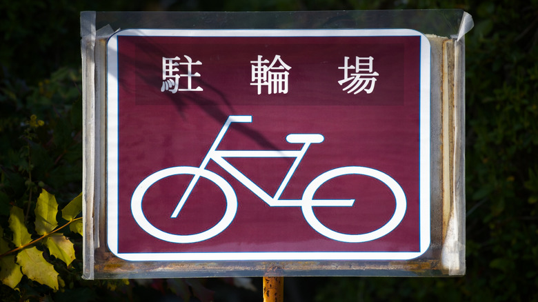 A Japanese street sign showing a bicycle with untranslated text above it.