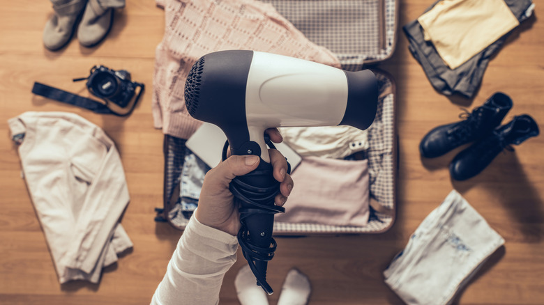 A woman packing a hair dryer ready for travel