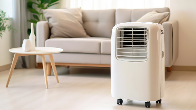 Portable air conditioner with wheels on the floor of a living room