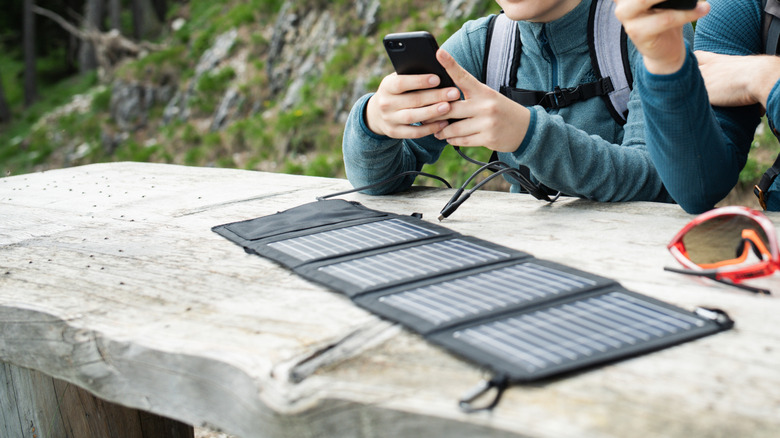 Person charging their phone directly from a portable solar panel