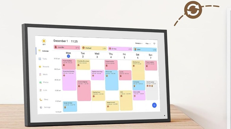 A black-framed digital calendar on a lightwooden table, displaying a color-coded schedule.