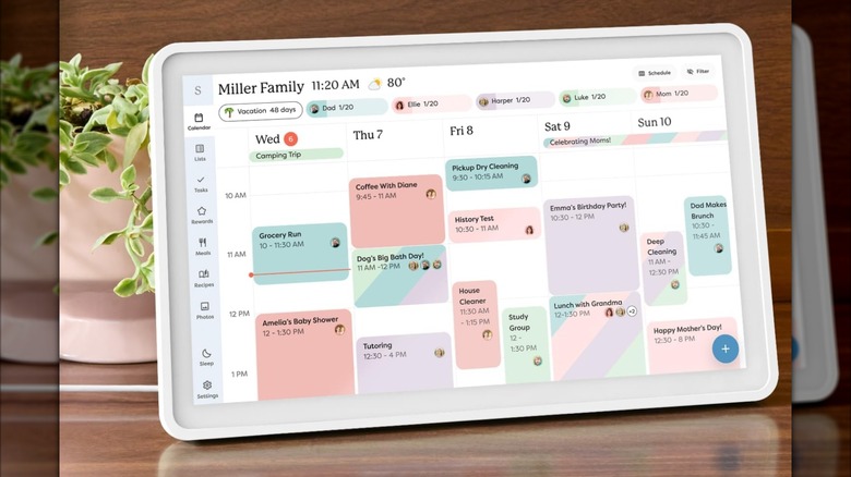 A digital calendar with a white frame sitting on a wooden table.