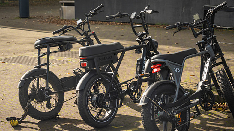 A line of three e-bikes parked on a street.