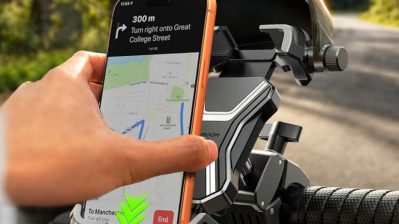 A hand placing a smartphone on a Joyroom bike phone mount on a bike.